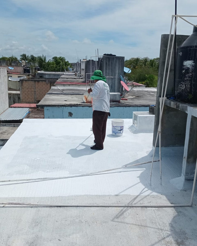 Azotea en proceso de impermeabilización con Converheat Caucho blanco, con tinacos y vista urbana al fondo
